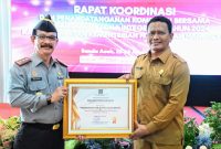 Kepala Kantor Kemenkumham Wilayah Aceh Dr.Drs.Meurah Budiman menyerahkan penghargaan program prioritas nasional dibidang merk dan hak cipta kepada Pemerintah Kabupaten Aceh Besar yang diterima oleh Staf Ahli Bidang Perekonomian Pembangunan dan Keuangan Ir.Makmun, MT Selasa (23/1/2024) di Hotel Grand Nanggroe Banda Aceh