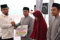 Pj Bupati Aceh Besar Muhammad Iswanto menyerahkan bonus kepada salah seorang juara MTQ Aceh Tahun 2023 di Simeulue pada momentum buka puasa bersama di Meuligoe Kota Jantho, Kamis, 21 Maret 2024.(Foto MC Aceh Besar)