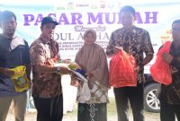 Kasi analis perdagangan Diskopukmdag Aceh Besar Abdul Hadi, SE menyerahkan paket secara simbolis paket pasar khusus kepada salah satu pembeli di Pasar Krueng Raya, Kecamatan Mesjid Raya, Aceh Besar, Kamis (6/6/2024) Foto : MC Aceh Besar