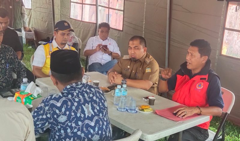 Pj Bupati Aceh Besar, Muhammad Iswanto mendengarkan laporan Kepala pelaksana BPBD Aceh Besar, Ridwan Jamil terkait distribusi air bersih saat meninjau Posko Pengendalian Siaga Darurat Kekeringan di halaman Kantor Camat Lhoknga, Kamis (11/7/2024). (Foto Acehstandar.com)