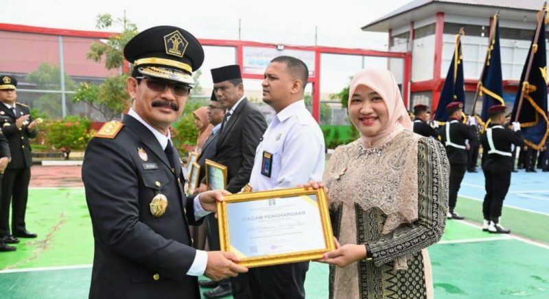 Pj Ketua Dewan Kerajinan Nasional Daerah Aceh Besar Cut Rezky Handayani, MM menerima Piagam Penghargaan Bidang Kekayaan Intelektual dari Kakanwil Kemenkumham Aceh, Dr. Drs. Meurah Budiman, S.H., M.H di Lapas Kelas II A, Gampong Bineh Blang, Kecamatan Ingin Jaya, Aceh Besar, Senin (19/8/202), Foto : MC Aceh Besar