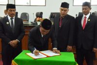 Bupati Aceh Besar H Muharram Idris disaksikan Wakil Bupati Drs H Syukri, Sekda Bahrul Jamil S.Sos, M.Si serta Pimpinan DPRK Aceh Besar menandatangani persetujuan Raqan Kabupaten Aceh Besar Tentang Perubahan APBK menjadi Qanun APBK-P Aceh Besar TA 2025, dalam sidang paripurna, di Gedung DPRK Aceh Besar, Kota Jantho, Selasa (30/9/2025) siang. FOTO/ MC ACEH BESAR