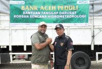 Direktur Utama Bank Aceh Syariah Fadhil Ilyas melakukan salam komando dengan Bupati Pidie Jaya Tgk H Syibral Malasyi, MA usai menyalurkan bantuan tanggap darurat kepada korban banjir di Kabupaten Pidie Jaya, Sabtu (13/12/2025). Foto Humas Bank Aceh Syariah