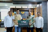 Direktur Utama Bank Aceh Fadhil Ilyas menyerahkan bantuan secara simbolis yang diterima oleh Sekda Aceh Muhammad Nasir, S.IP, MPA disela rapat Koordinasi Penyusunan Dokumen Rencana Rehabilitasi dan Rekontruksi Pasca bencana Provinsi Aceh di kantor Gubernur Aceh Jumat (2/1/2026).