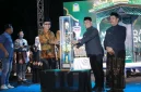 Bupati Aceh Besar H. Muharram Idris menyerahkan piala bergilir kepada Camat Peukan Bada, Salamuddin ZM, SE usai menjadi Juara Umum MTQ ke-35, Jumat (30/10/2026) malam.