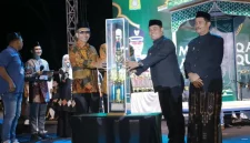 Bupati Aceh Besar H. Muharram Idris menyerahkan piala bergilir kepada Camat Peukan Bada, Salamuddin ZM, SE usai menjadi Juara Umum MTQ ke-35, Jumat (30/10/2026) malam.