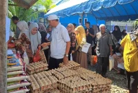 Warga Jantho Makmur mengantre membeli sembako pada kegiatan Gerakan Pangan Murah di halaman Kantor Camat Kota Jantho, Kamis (15/10/2026).